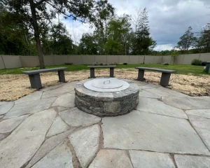 Outdoor wood burning firepit with surrounding rustic stone seating.